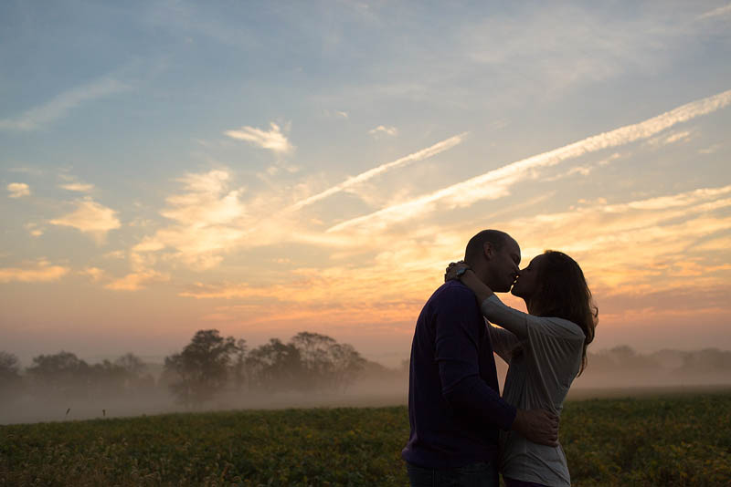 couple cuddles during sunrise at frederick engagement photography session with jacqie q