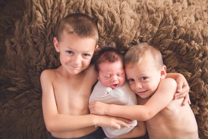 newborn with brothers on flokati rug portrait frederick