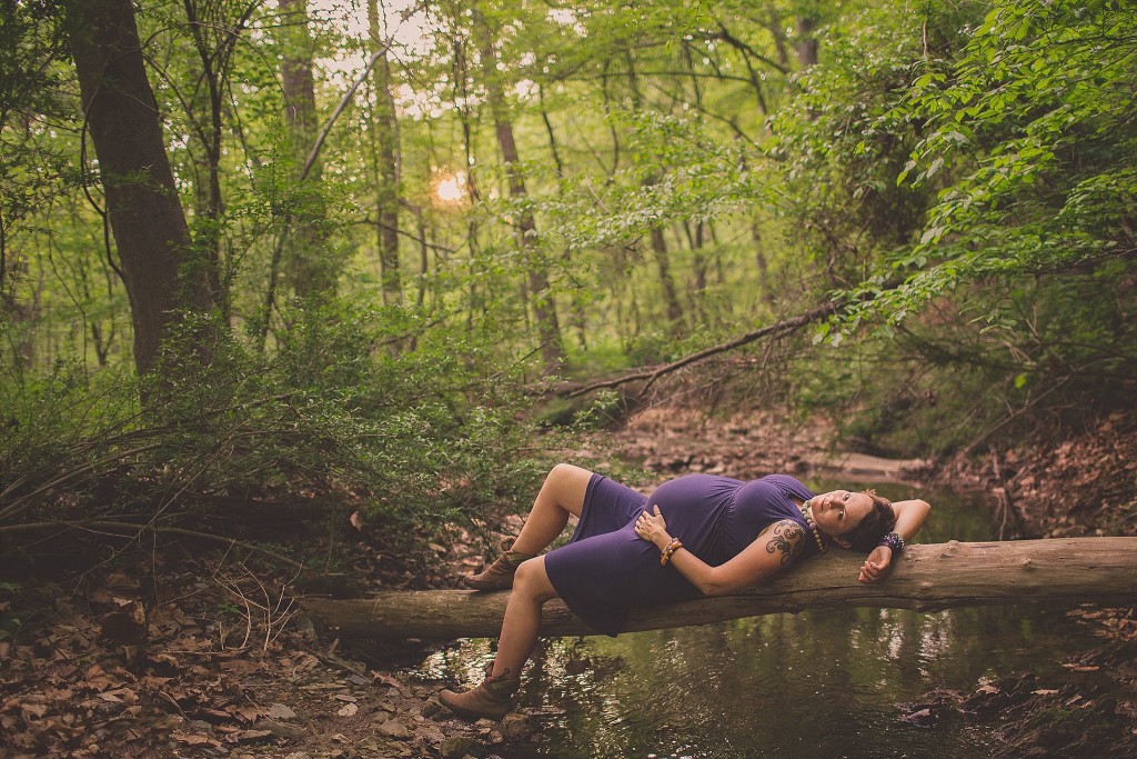 pregnant woman lies on log during frederick maternity photography session