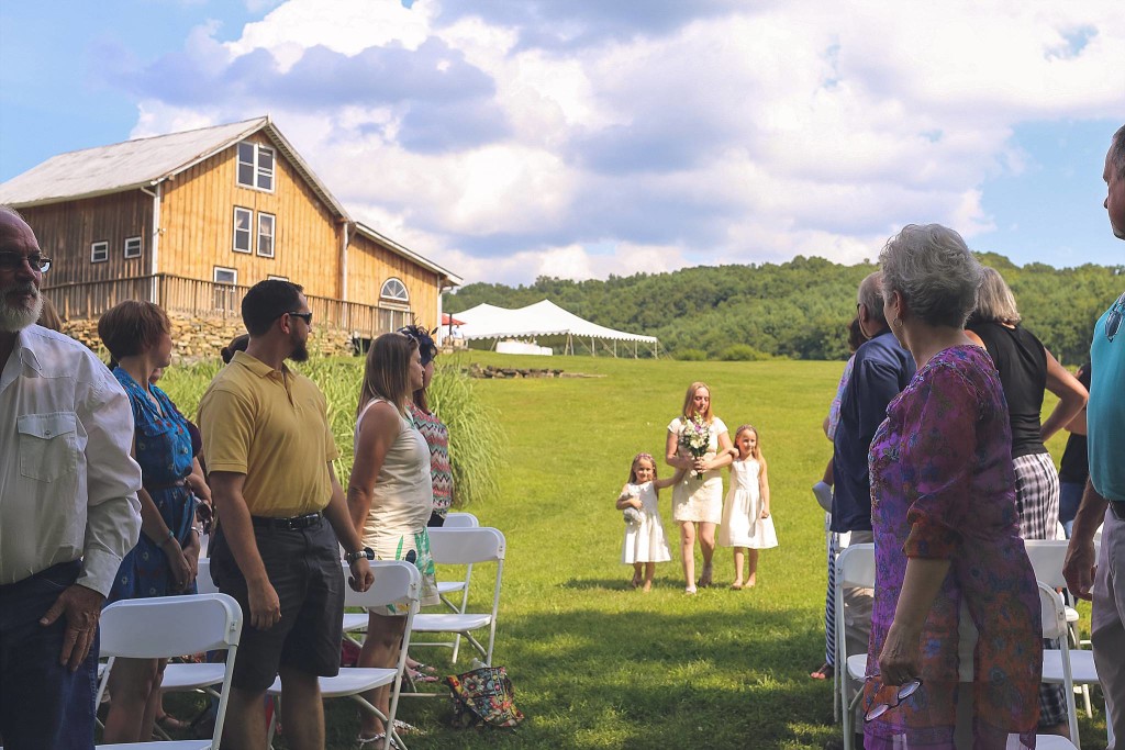 bride and daughters walk down aisle at outdoor wedding