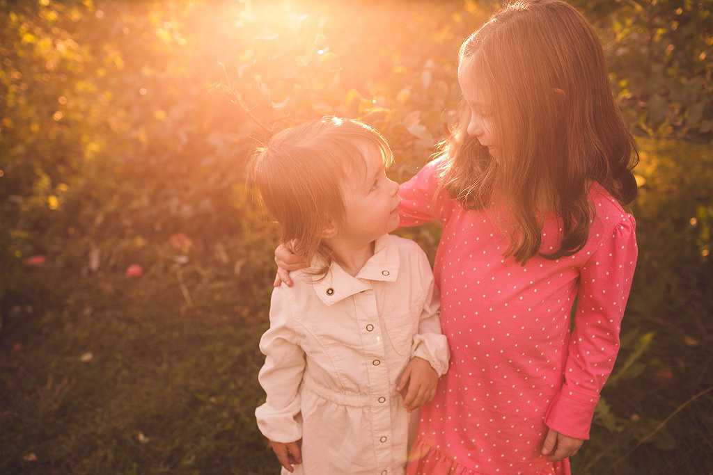 sisters hug in apple orchard in maryland at family photography session