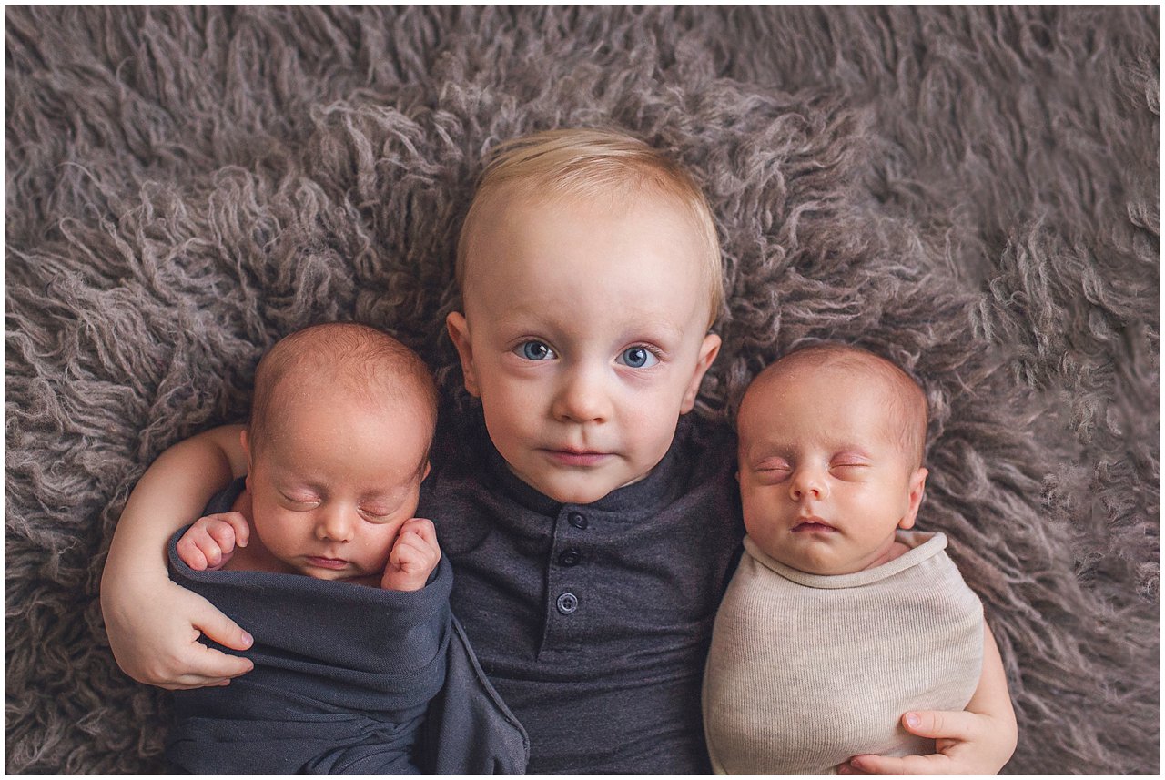 three times the boy love as little brother holds twin newborn brothers