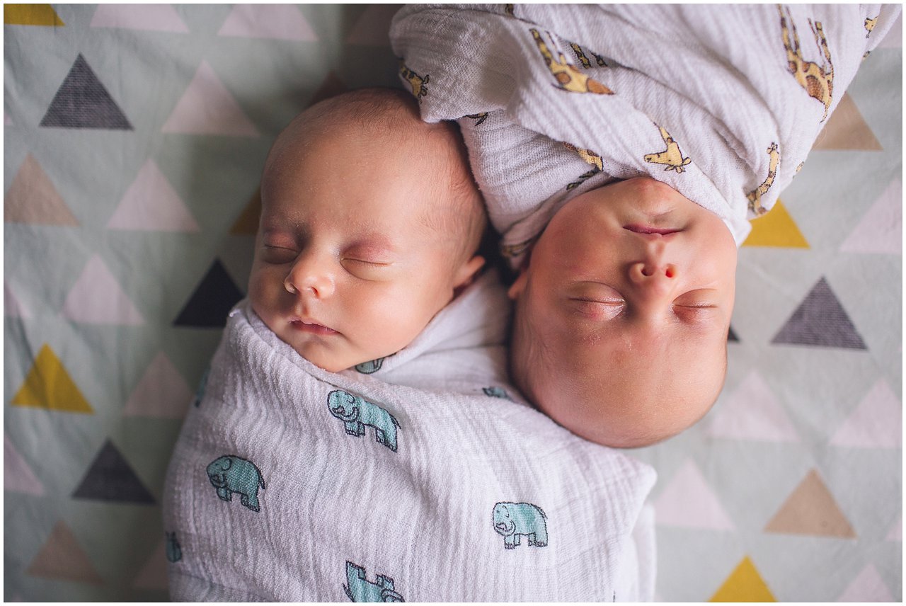 Twin newborn boys head to head in crib