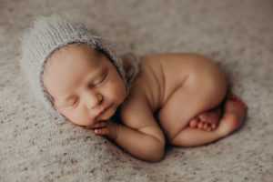 cumberland newborn photographer poses baby boy with bonnet